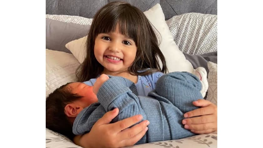 Isabela Garza sostiene a su hermano, Jason Thomas Garza, quien nació el 19 de julio de 2021 en el mismo hospital donde murió su padre el 4 de mayo de 2021.