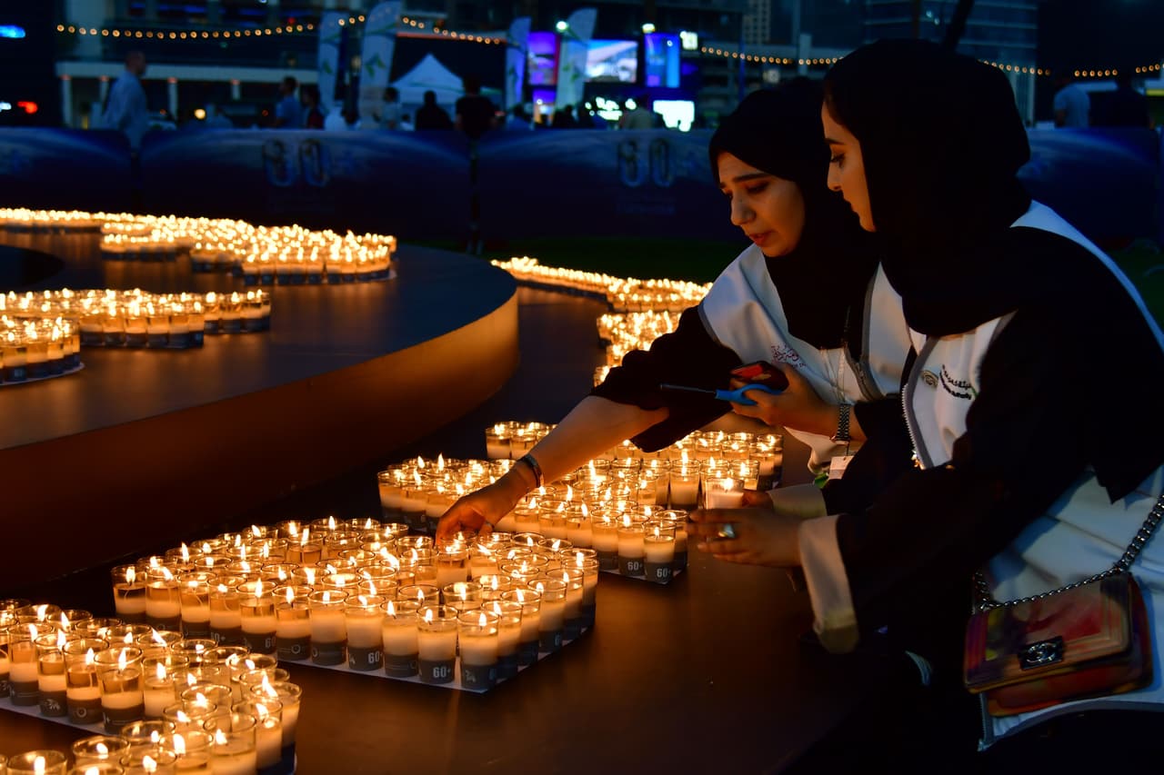 Dos mujeres encienden velas después de que se apagaran las luces de los edificios en Dubái.