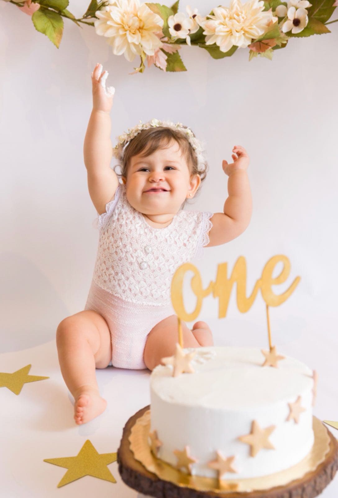 Silvanita se ve muy feliz, rodeada de flores y con su pastel de un año.