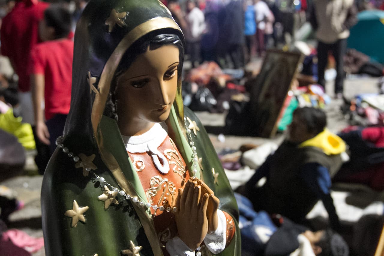 Personas cargan imágenes y figuras de la Guadalupe en diferentes tamaños.