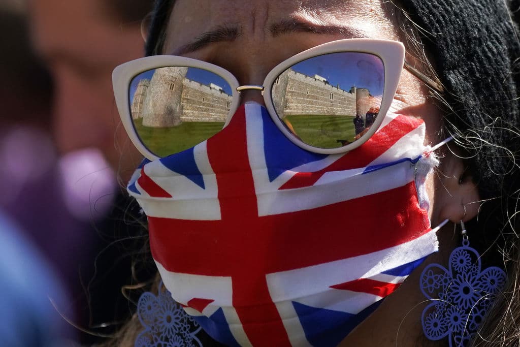 Una mujer con mascarilla de la bandera británica mira con gesto afligido hacia el Castillo de Windsor durante dos minutos de silencio en honor a Felipe de Edimburgo.
