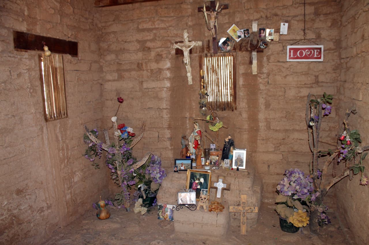 Curces, fotos y adornos dentro de las paredes de adobe.