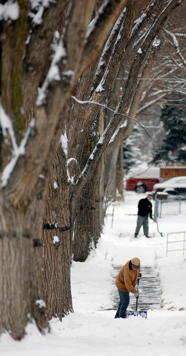 Varias personas tratan de limpiar la acera en Bismarck, en North Dakota.