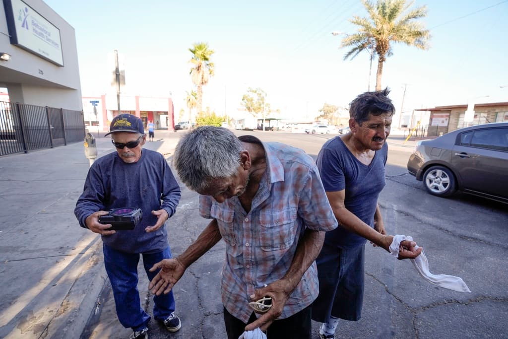 Tres personas sin hogar reciben toallas mojadas de Maribel Padilla, de la Brown Bag Coalition, en Calexico, California.