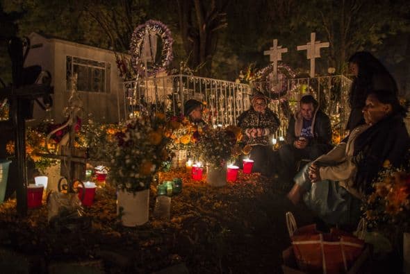 Esta familia de Tzintzuntzan, Michoacán hace 'guardia' la noche del 1 de noviembre en uno de los panteones municipales.