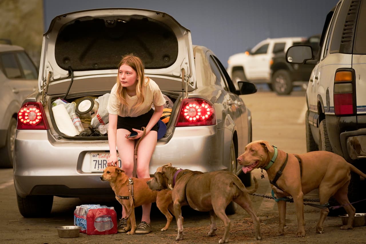 Kelsey Mueller, de 16 años, habitante de Armona, California,
<b>acaricia a sus perros mientras espera con su familia ser escoltada </b>desde la montaña mientras el incendio de Creek arde cerca en Shaver Lake, California.
<br>