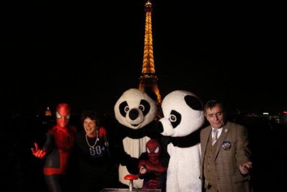 Gente vestida como pandas y como el hombre araña junto a personalidades de WWF antes de apagar la iluminación de la Torre Eiffel.