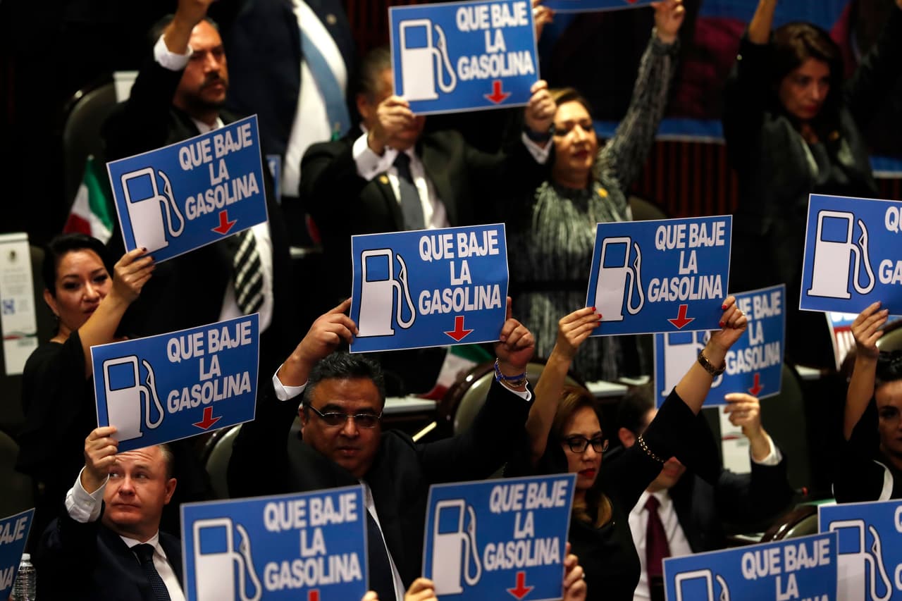 Un grupo de legisladores sostiene carteles de protesta con un mensaje que pide que bajen el precio de la gasolina.