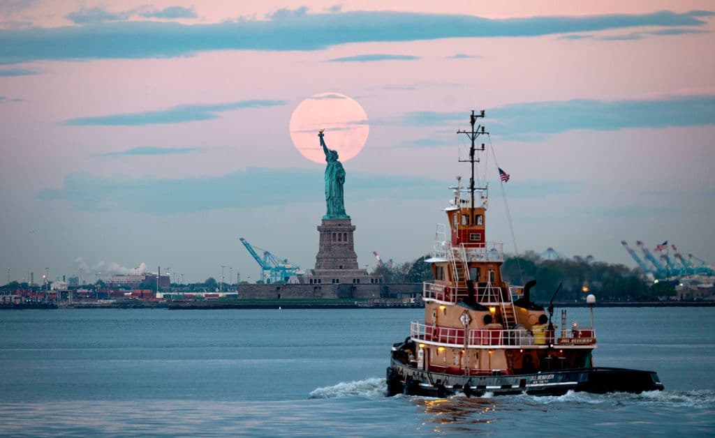 Una imagen de la Superluna detrás de la Estatua de la Libertad, en Nueva York, en la mañana del jueves. Cerca de las 6:45 am ET del jueves apareció justo frente al Sol (en longitud terrestre). Pero el efecto 'Superluna' continuó hasta este viernes por la mañana.