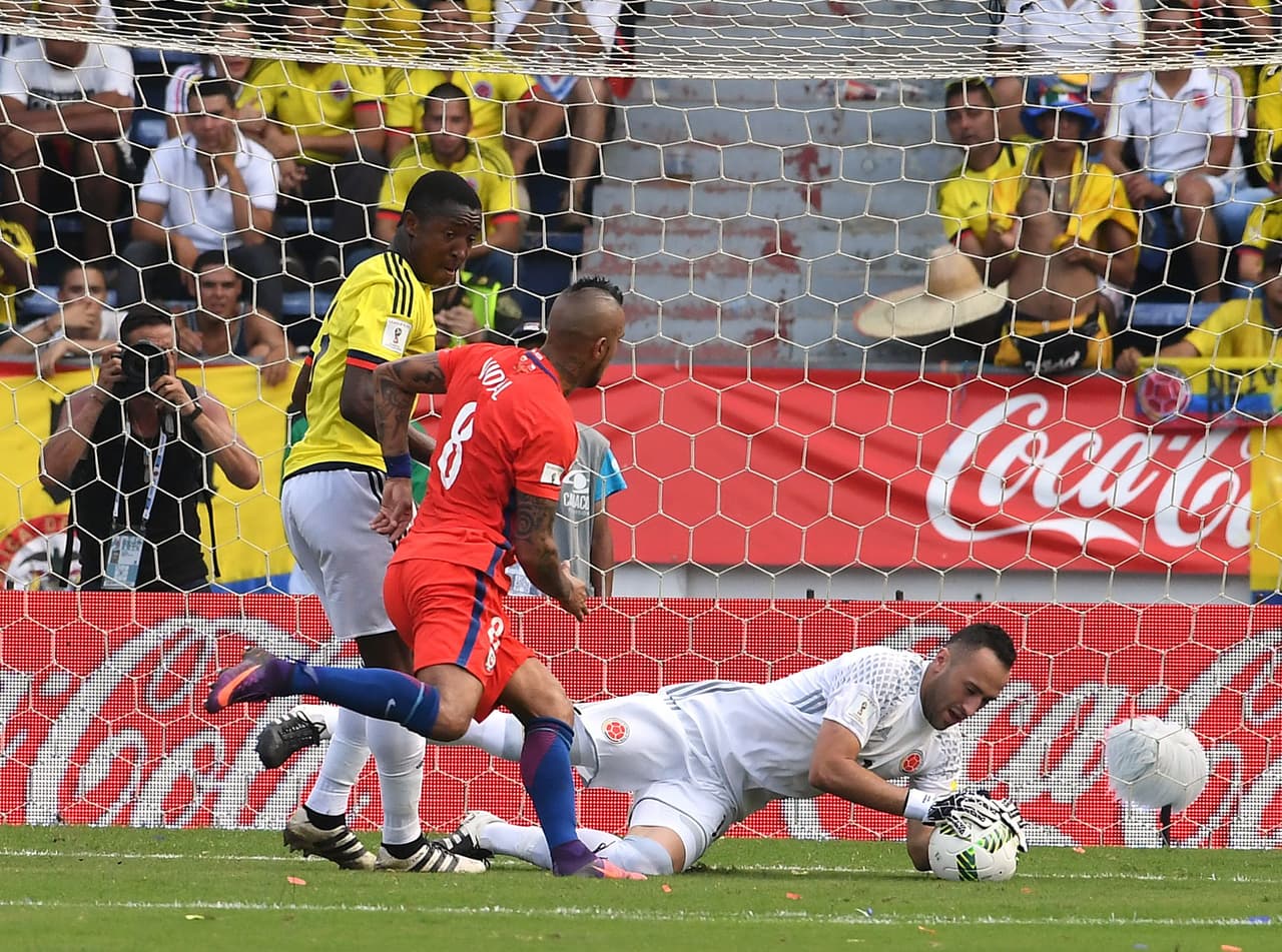Colombia's goalkeeper David Ospina grabs a ball over the attack by Chile's midfielder Arturo Vidal (C) during their 2018 FIFA World Cup qualifiers football match in Barranquilla, Colombia, on November 10, 2016. / AFP / Luis Acosta (Photo credit should read LUIS ACOSTA/AFP/Getty Images)