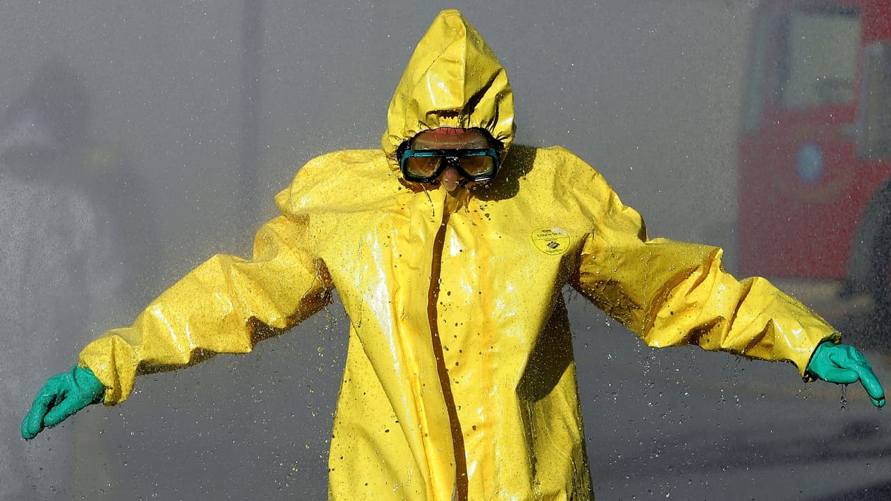 COLMA, CA - FEBRUARY 1: A man wearing a hazardous materials suit walks through a decontamination shower during a weapons of mass destruction training workshop February 1, 2005 in Colma, California. Representatives from several San Mateo County police and fire departments took part in the one day training to prepare for a chemical or biological attack. (Photo by Justin Sullivan/Getty Images)