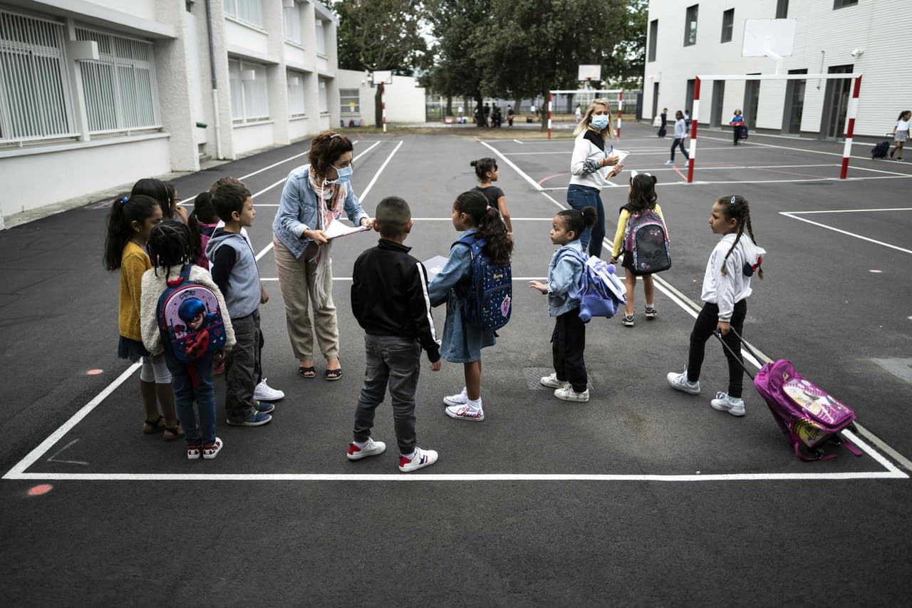 Children listen to a teacher wearing a protective mask in the playground at the Clement Falcucci elementary school in Toulouse, southwestern France, on September 1, 2020, on the first day of the start of the school year amid a resurgence of the Covid-19 epidemic. - French pupils go back to school on September 1 as schools across Europe open their doors to greet returning pupils this month, nearly six months after the coronavirus outbreak forced them to close and despite rising infection rates across the continent. (Photo by Lionel BONAVENTURE / AFP) (Photo by LIONEL BONAVENTURE/AFP via Getty Images)