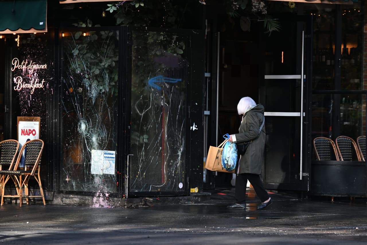 Una mujer pasa junto a un bar vandalizado al día siguiente de una manifestación.