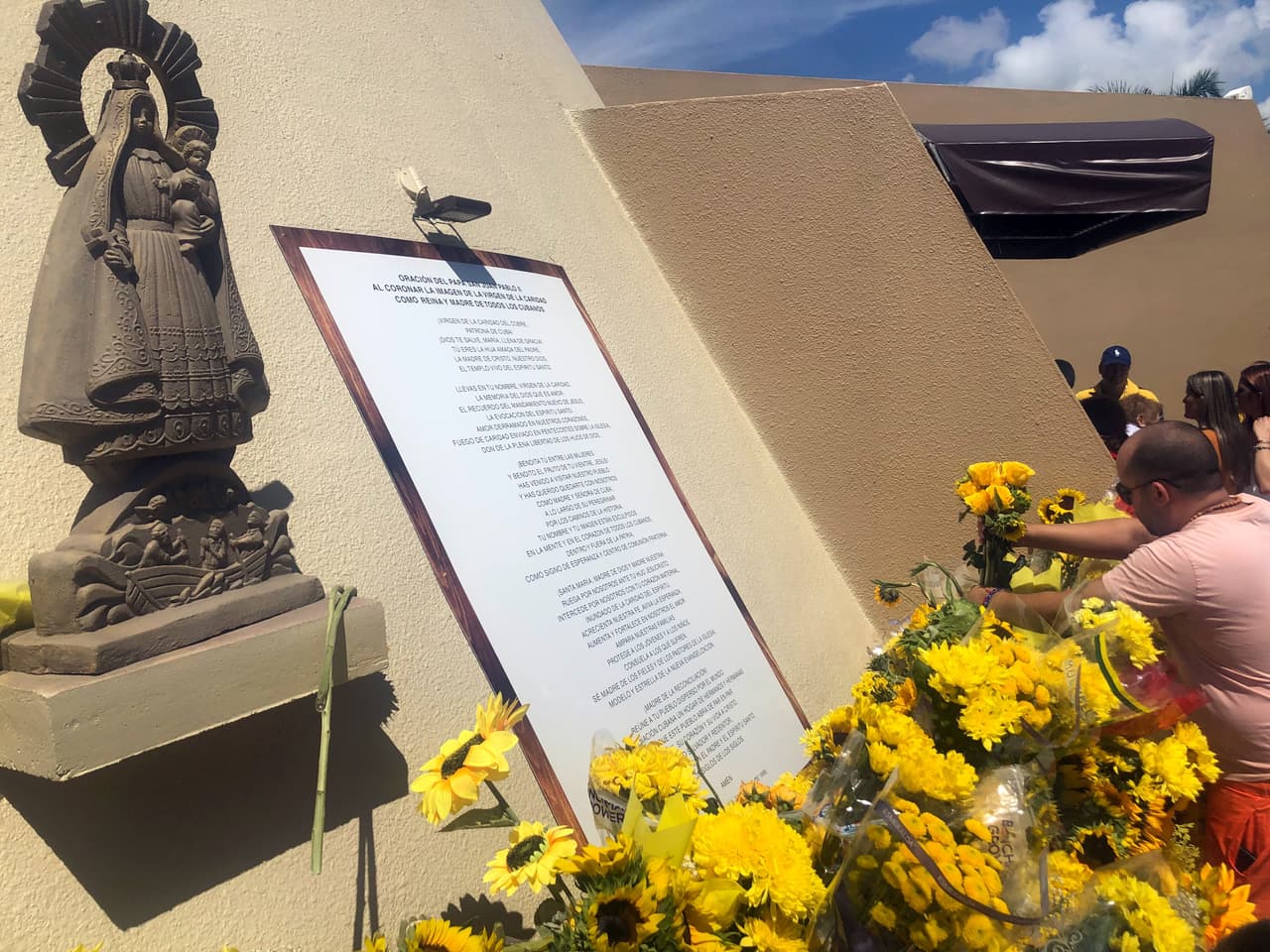 Cientos de feligreses llevan girasoles para obsequiar a la Virgen en las afueras de la Ermita de la Caridad.