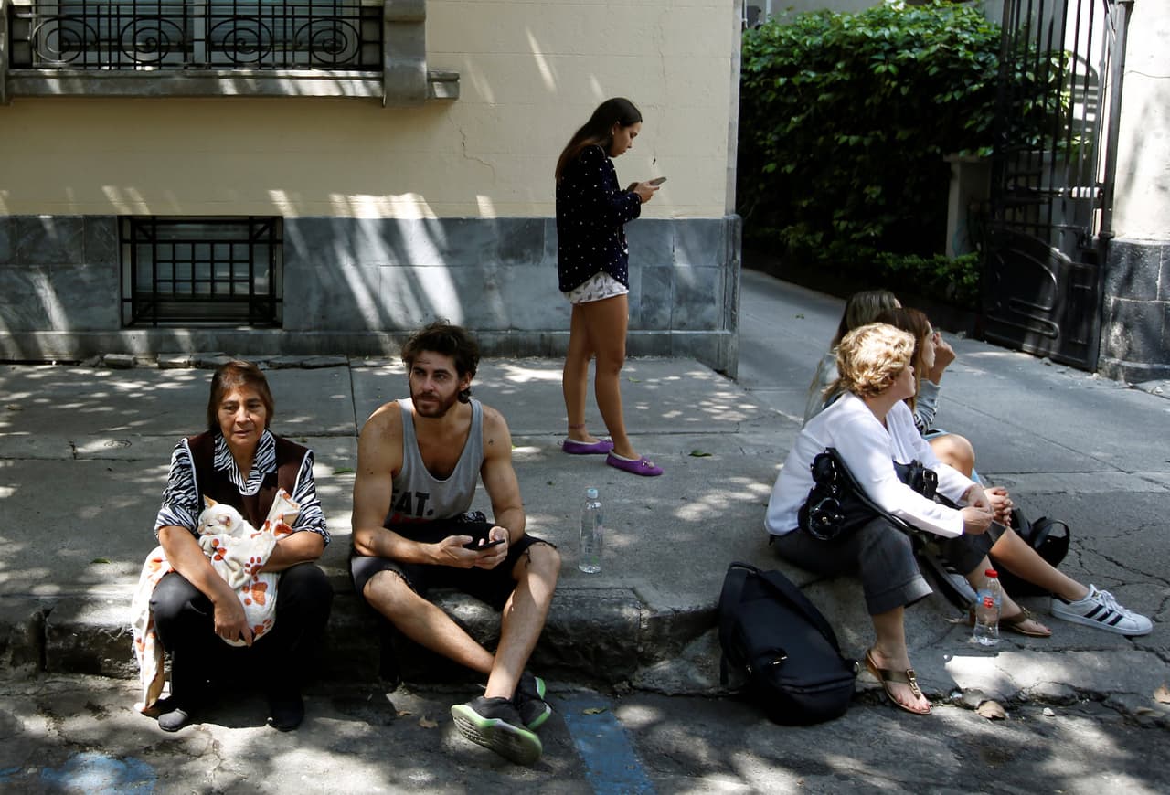 People sit on a sidewalk after an earthquake hit Mexico City, Mexico September 19, 2017. REUTERS/Carlos Jasso