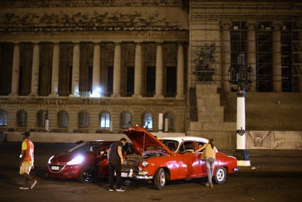 Un coche nuevo de la marca Peugeot aparca a lado de un Chevrolet Bel-Air 1954.