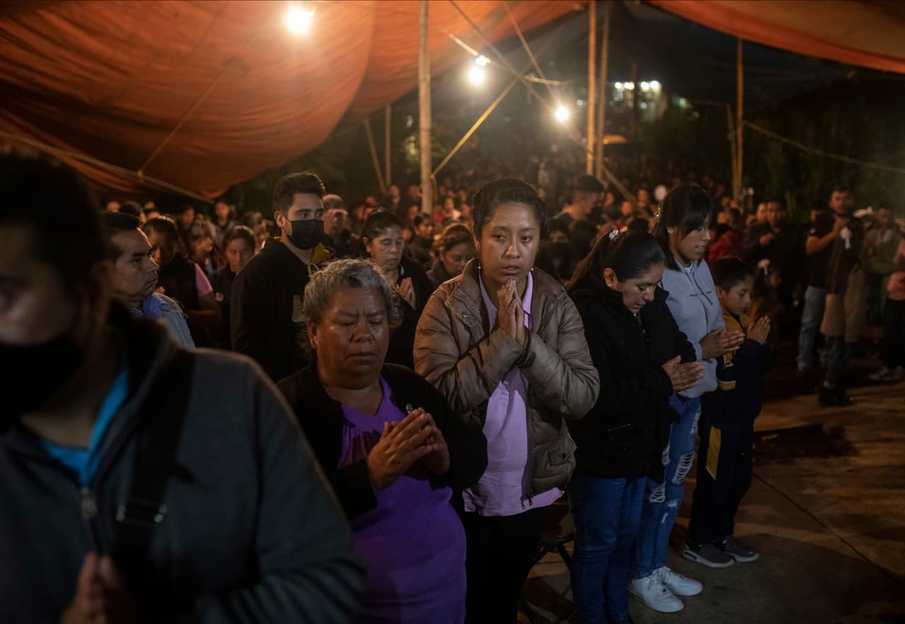 Familiares y amigos rezan mientras esperan la llegada de los féretros con los restos mortales de Jair Valencia, Misael Olivares, y Yovani Valencia.