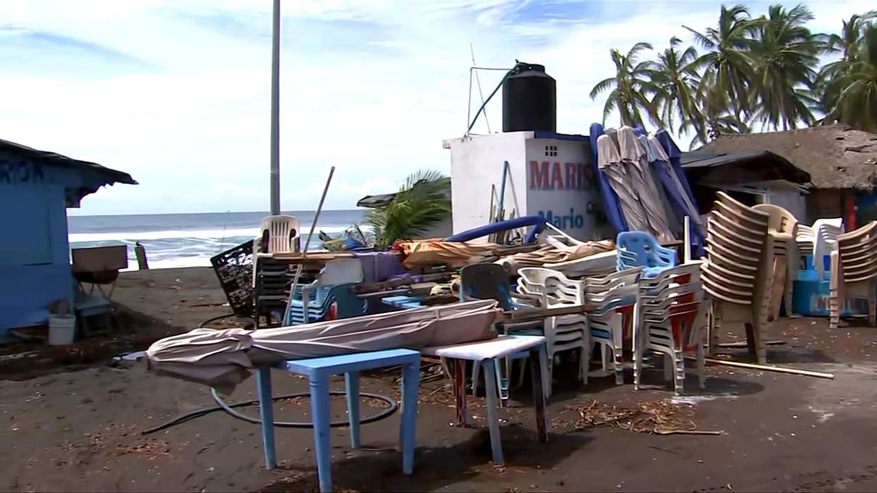 Habitantes en una playa de Colima, México, buscan sus pertenencias entre la arena por oleaje intenso del huracán Simon