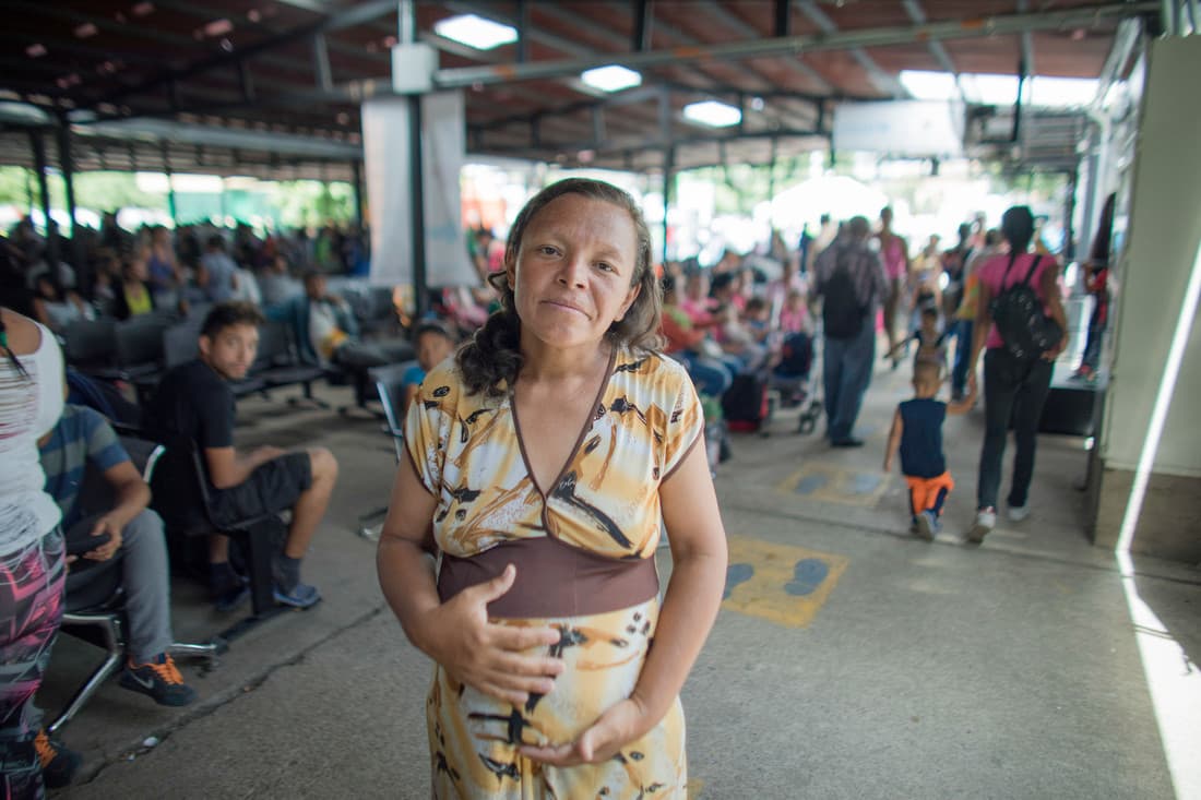 Para mayo de 2019, Karina Ríos tiene 37 años y está embarazada de su tercer hijo. En la imagen se encuentra en uno de los puestos de atención de la Cruz Roja, en la frontera entre Venezuela y Colombia. Se acercó al fotógrafo Josh Estey y el equipo de CARE porque quería "hablar de lo que le está pasando a las mujeres y la niñas, especialmente a las embarazadas", como ella. "Dormimos en la calle porque a mi esposo no le permiten la entrada en los albergues. Somos mi esposo, mis dos niños y yo. Tengo 8 meses de embarazo. En la calle: no somos animales.
<b>Conocí a una niña de 14 años en la ruta, que era acosada continuamente por hombres: todos le ofrecían dinero por sexo. </b>Ninguna niña merece ese trato".