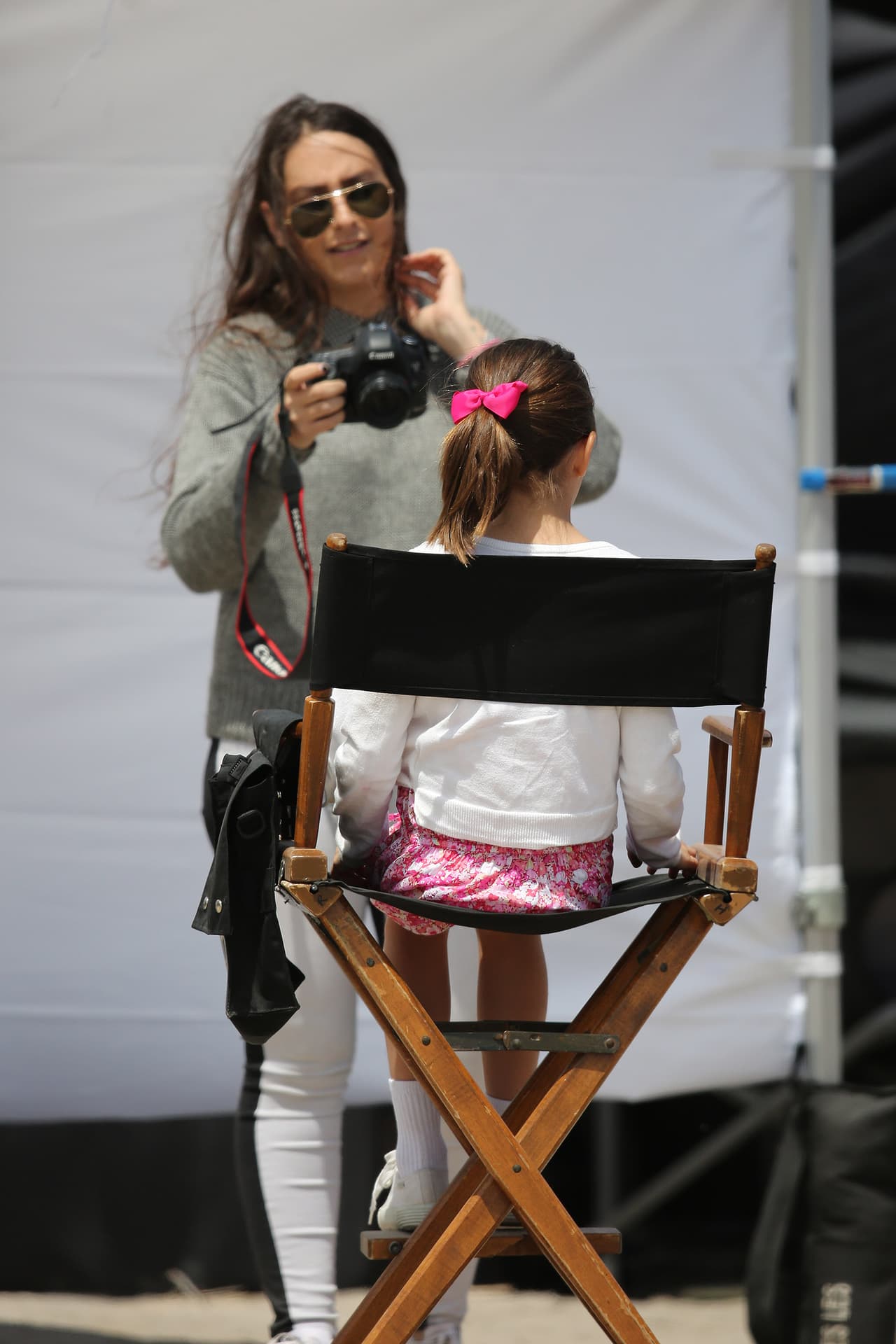Suri aguarda en su silla de director, muy tranquila en el set mientras su madre, Katie, trabaja.