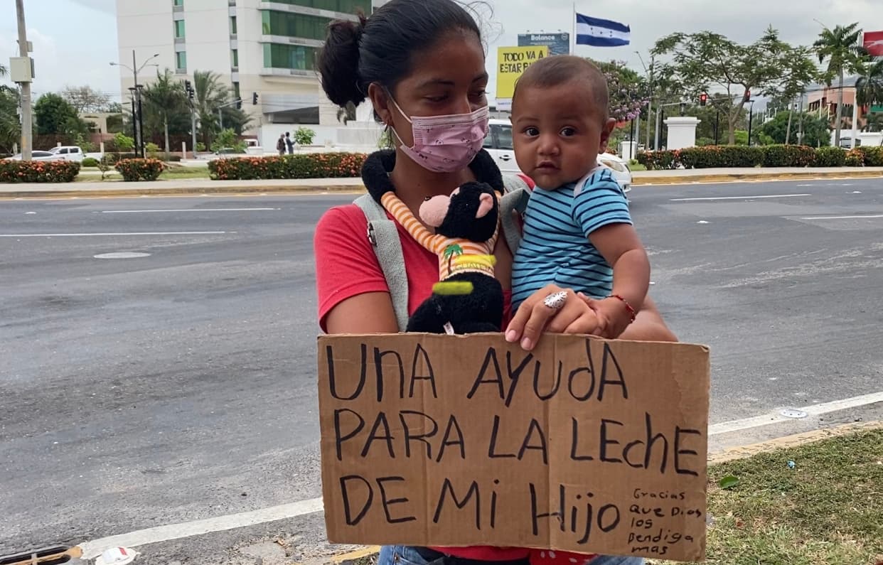 Una madre con su hijo pide ayuda al lado de la carretera en Sam Pedro Sula.