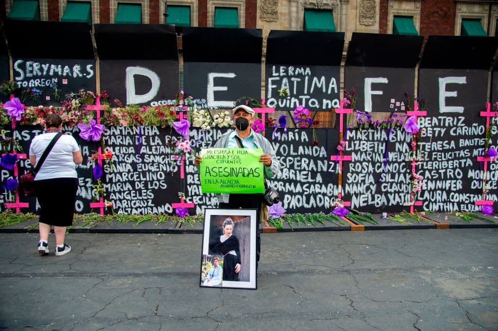 En la imagen, un hombre sostiene un cartel en el que reclama el feminicidio de su esposa, Graciela, y su hija, Sol, frente a la valla que instaló el gobierno federal de México en el Zócalo. El año 2020 fue particularmente violento a causa de la pandemia de 
<a href="https://www.univision.com/temas/coronavirus">covid-19</a>. Según informaron las autoridades, en los últimos 12 meses, se reportaron 
<b>143 llamadas por hora a causa de la violencia sexual y familiar</b>.