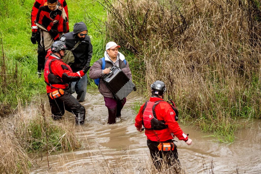 Trabajadores de búsqueda y rescate evacuan a hombres de un campamento para personas sin hogar que quedó rodeado por las inundaciones del río Guadalupe el domingo 4 de febrero de 2024 en San José, California (Foto AP/Noah Berger).