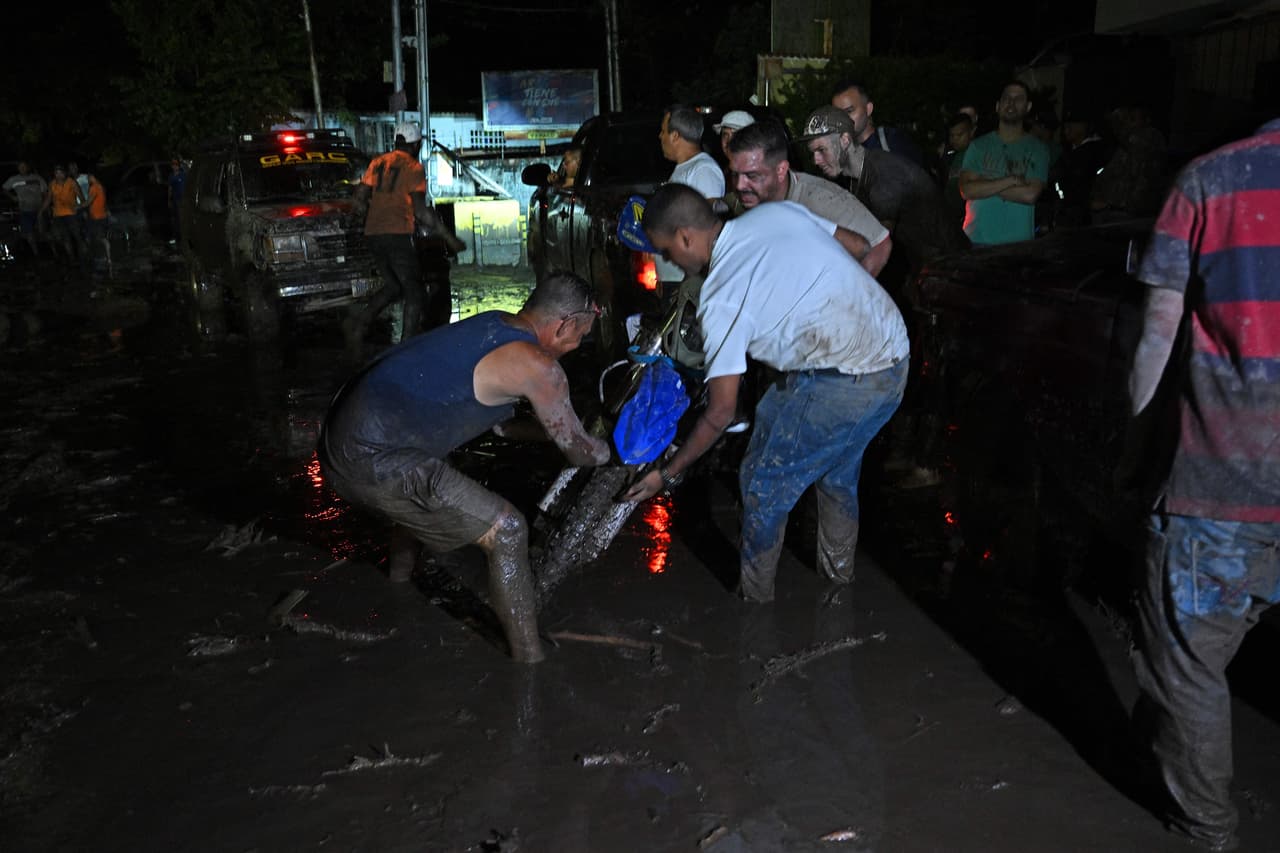 Personas intentan retirar una motocicleta atascada en el barro tras el alud en El Castaño.