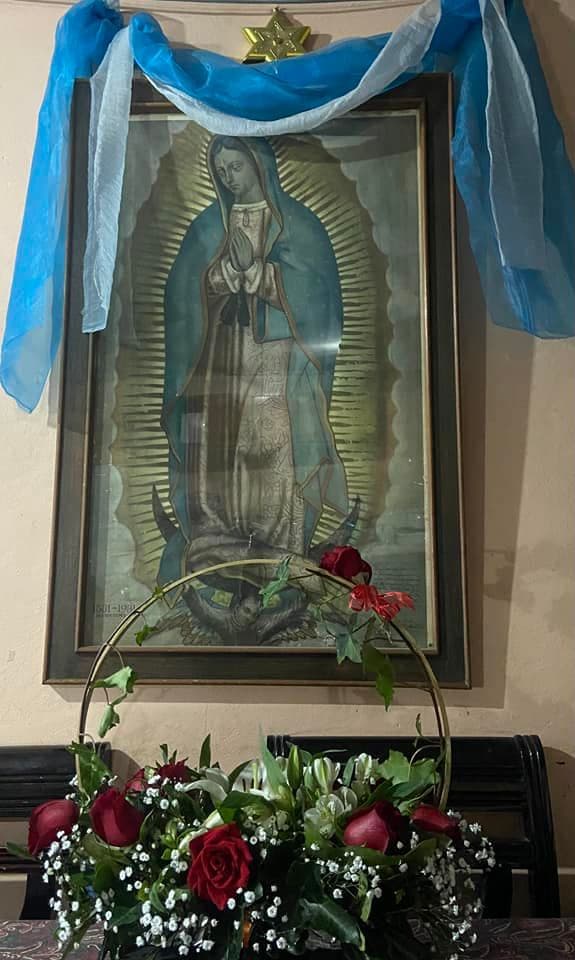 Una canasta de rosas rojas y un manto celeste decoran la imagen de la Virgen de Guadalupe de Karmen Caballero.