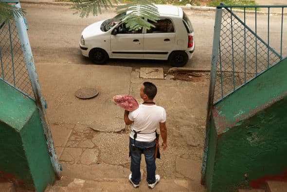 Un carnicero promueve su mercancía en la acera frente al Mercado Agropecuario en un intento por mejorar el negocio.