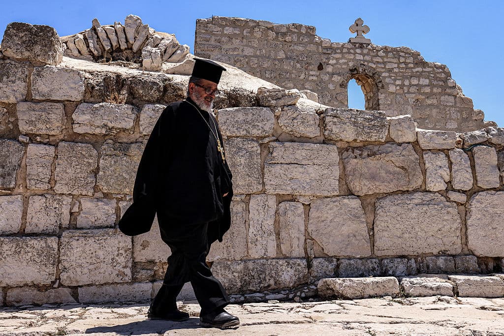 Un clérigo ortodoxo griego camina junto a la Iglesia de San Jorge, del siglo V, en la aldea cristiana palestina de Taybeh, al noreste de Ramala en Cisjordania ocupada, el 14 de julio de 2025, durante una visita de altos representantes de diversas denominaciones cristianas.