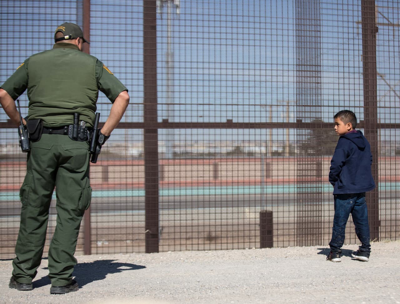 Un niño guatemalteco ve al oficial de la Patrulla Fronteriza mientras él le hace preguntas a su padre.