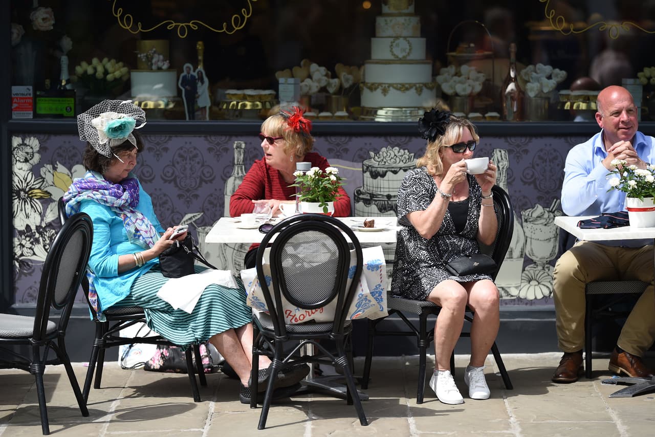 Con sus característicos sombreros, este trío de damas deleitó su paladar en un café, en 'High Street', donde el ambiente festivo se transmite con imágenes de los novios y hasta un pastel de bodas.
