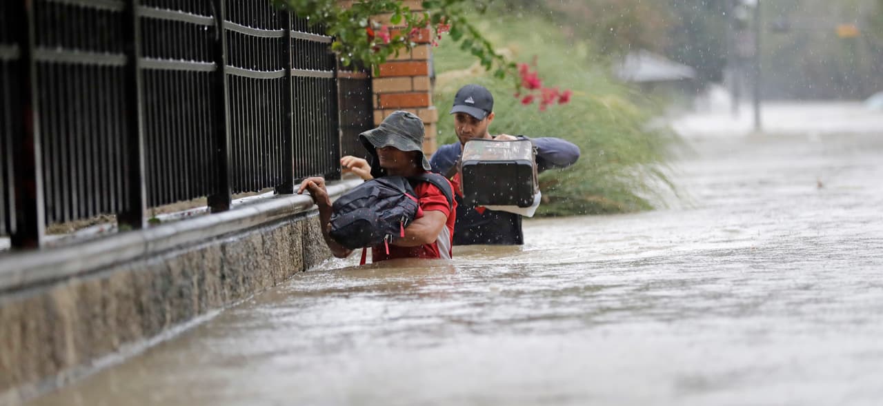 Residentes caminan por una calle inundada de Houston, donde la lluvia no se detiene.