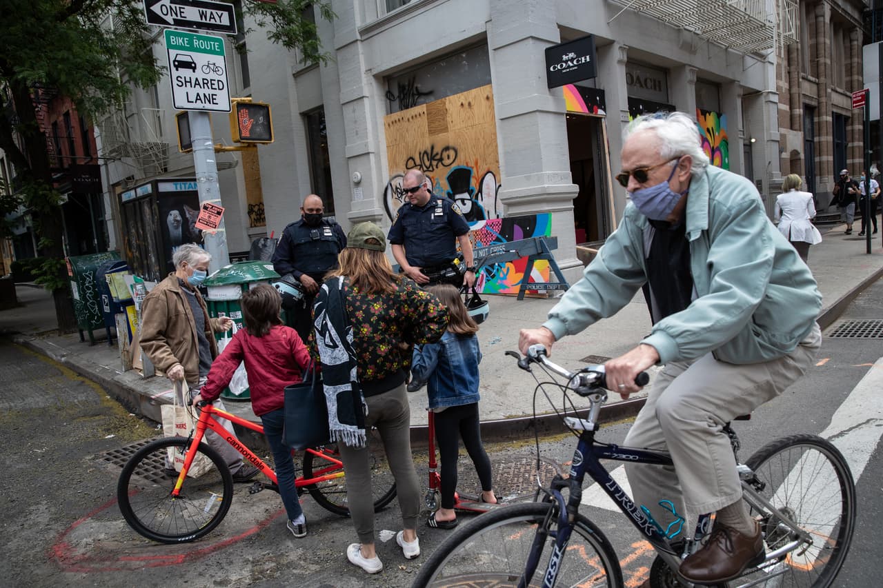 Policías de Nueva York hablan con residentes del vecindario frente a una tienda de bolsos y zapatos Coach la mañana después de que fue saqueada en el vecindario Soho de Manhattan el 1 de junio de 2020 en la ciudad de Nueva York.