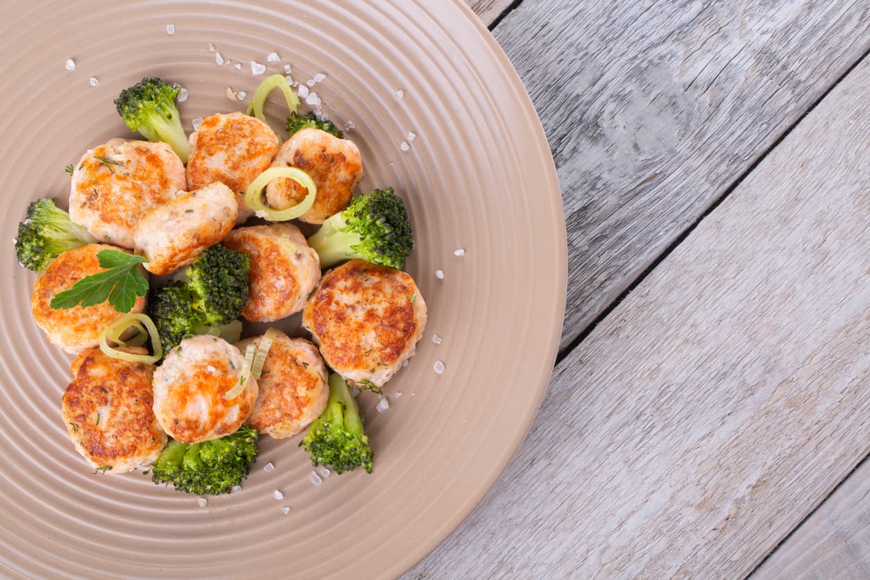 Plate of salmon meatballs with vegetables on a wooden table