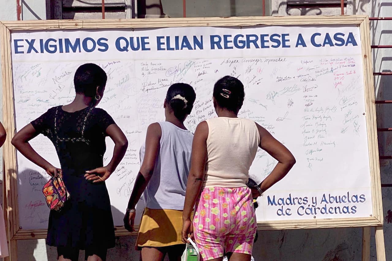 Unas mujeres miran las firmas de personas que apoyan el regreso de Elián González a la isla. En Cárdenas, Cuba, el 6 de diciembre de 1999. El niño había sido llevado en balsa a Miami por su madre, quien murió en la travesía. Él se encontraba en manos de parientes contra la voluntad de su padre.