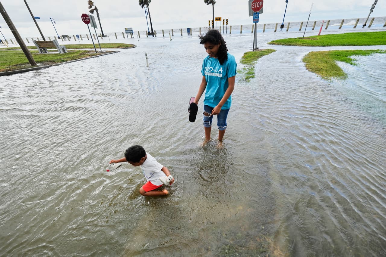 Kobe Crossley, de 3 años, y Amaya Crossley, de 12, juegan entre las aguas que inundan Lakeshore Drive, junto al lago Pontchartrain, mientras la tormenta tropical Bertha se acerca a la costa de Luisiana el miércoles 22 de julio de 2026, en Nueva Orleans. (Foto AP/Gerald Herbert)