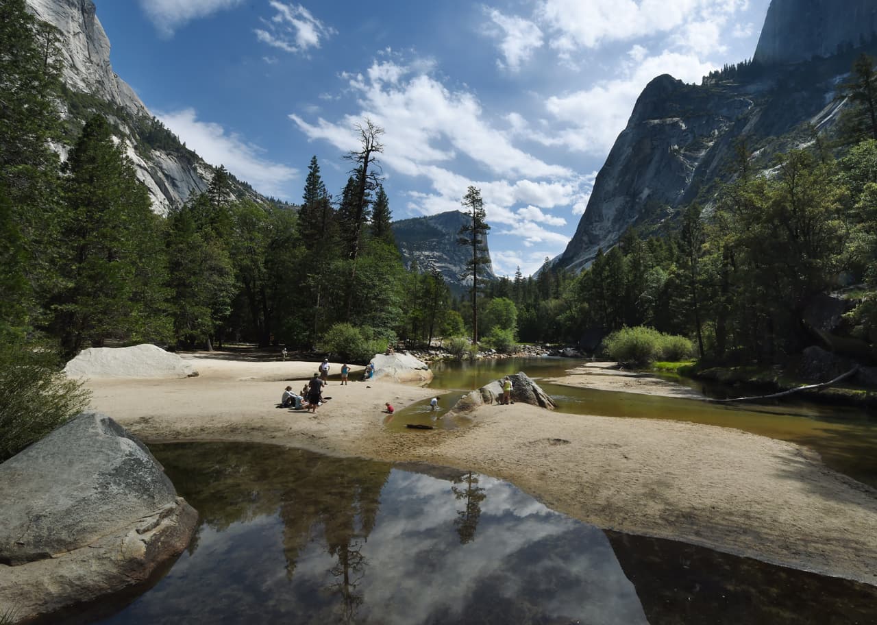 People picnic on the exposed sandy bottom of Mirror Lake that is normally underwater and used by visitors to photograph reflections of the Half Dome rock monolith at Yosemite National Park in California on June 4, 2015. At first glance the spectacular beauty of the park with its soaring cliffs and picture-postcard valley floor remains unblemished, still enchanting the millions of tourists who flock the landmark every year. But on closer inspection, the drought's effects are clearly visible. AFP PHOTO/MARK RALSTON (Photo credit should read MARK RALSTON/AFP/Getty Images)