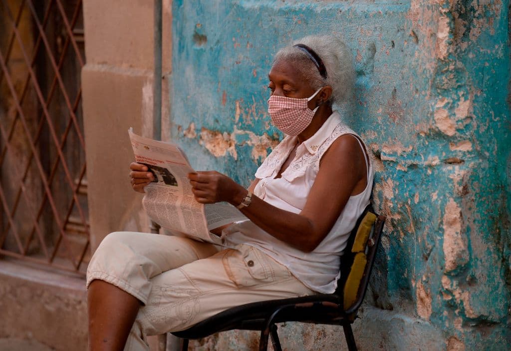 Una mujer con mascarilla lee el diario oficialista Granma en una calle de La Habana.