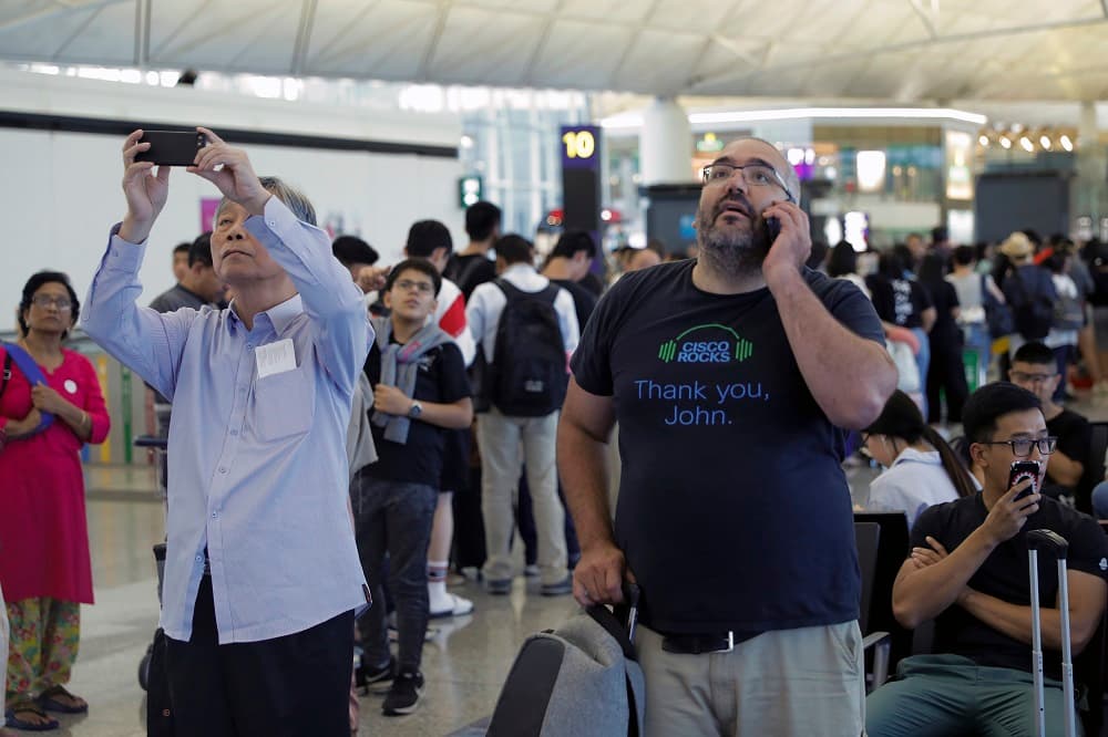 Las carreteras que conducen al aeropuerto han quedado hoy colapsadas después de que los manifestantes se dirigiesen hasta el Aeropuerto Internacional de Hong Kong en autobús, de acuerdo con el rotativo local 
<i>South China Morning Post</i>. En la fotografía, viajeros revisan el estatus de sus vuelos.