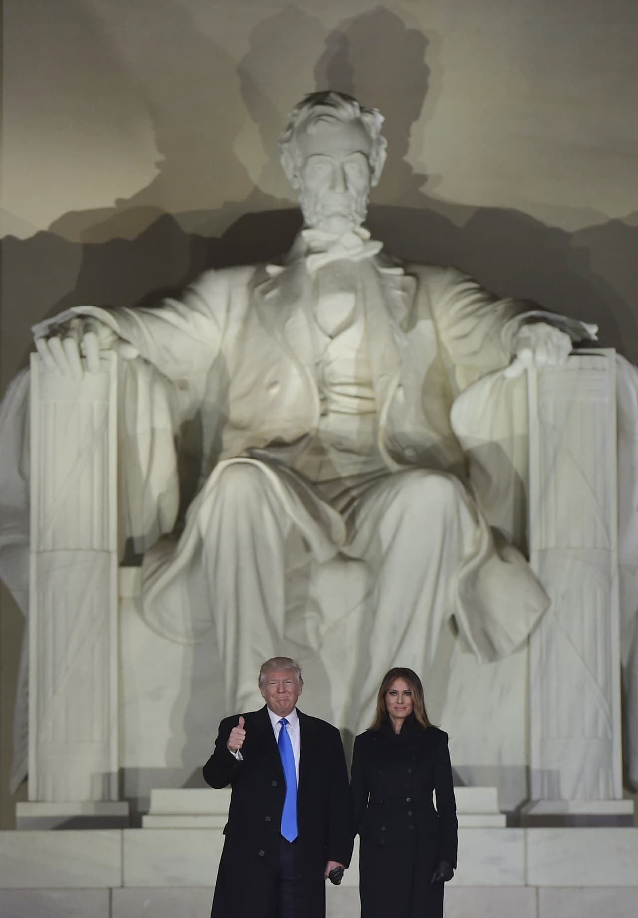 Ante la figura de Abraham Lincoln Donald Trump hace la señal de triunfo.