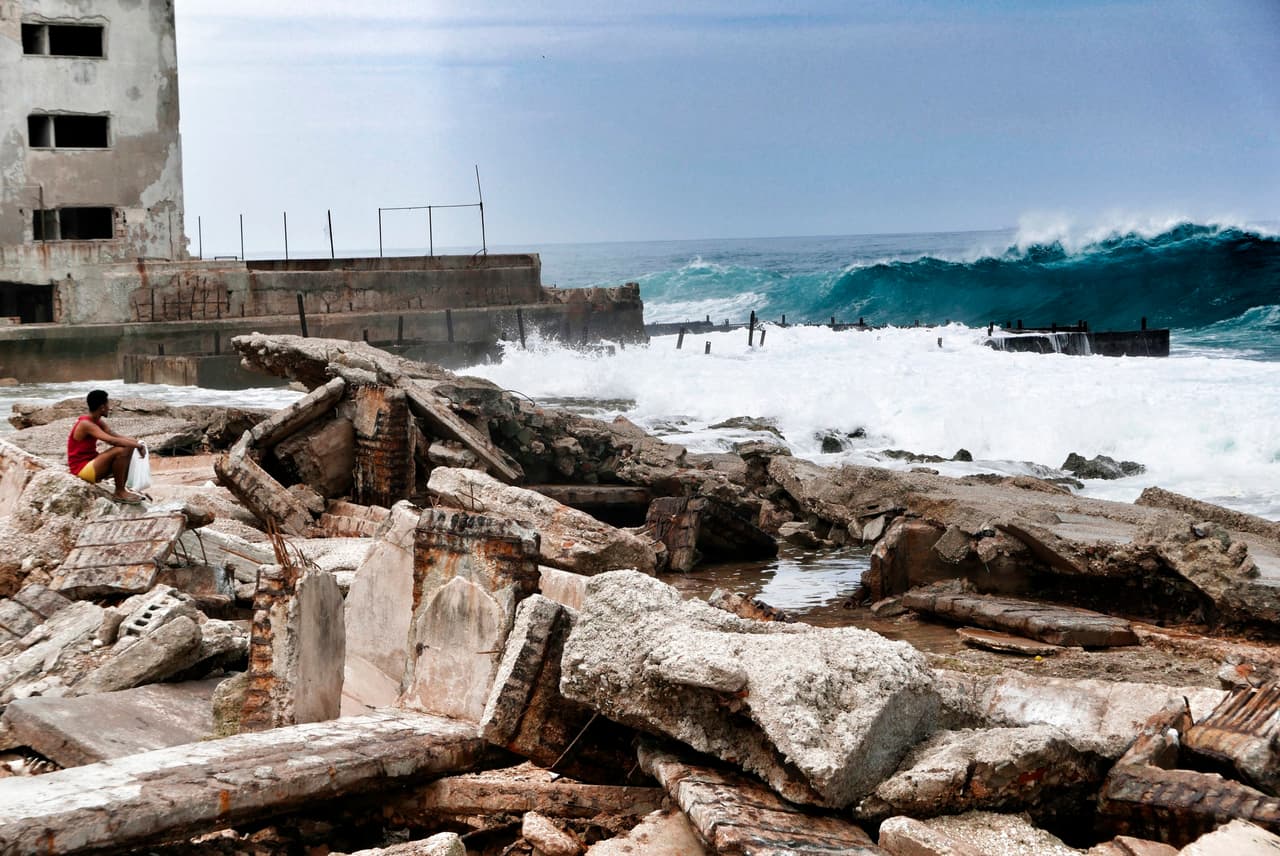 Un hombre sentado en medio de los escombros frente al mar en La Habana. Según las cifras oficiales, estos 10 muertos son la peor cifra de víctimas fatales en huracanes en Cuba 
<b><a href="http://www.nhc.noaa.gov/data/tcr/AL042005_Dennis.pdf" target="_blank">desde que el paso de Dennis en 2005, que mató a 16 personas</a></b>.