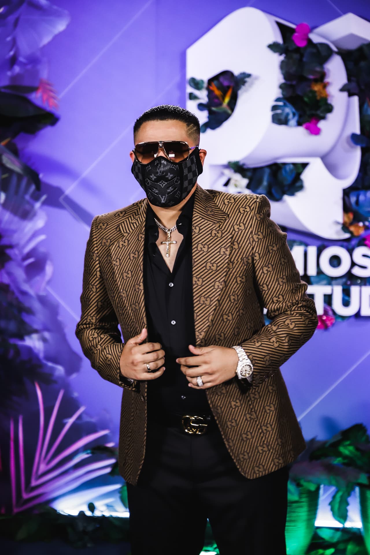 Además de la mascarilla de alta costura, el intérprete llevó un enorme crucifijo de oro colgando del cuello, un reloj y un anillo con brillantes, cinturón también Gucci y lentes oscuros.