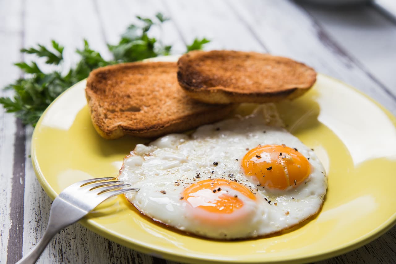 Fried eggs and toasted breads on a yellow plate