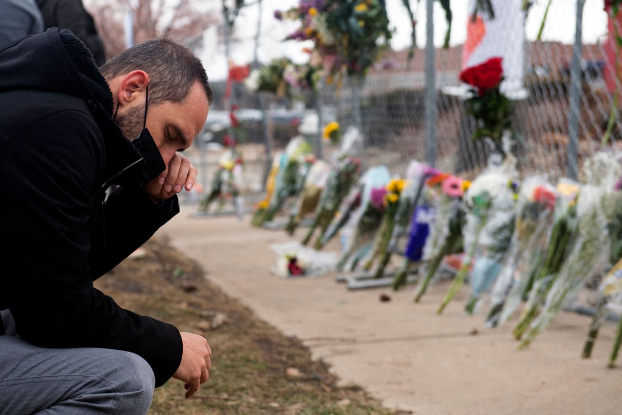 Otra imagen de una escena de dolor en el memorial a las víctimas mortales del tiroteo del lunes en Colorado. El más joven de las víctimas acababa de cumplir 21 años; la mayor tenía 65. Algunos estaban solteros, otros casados. Algunos eran clientes de King Sooper, otros empleados de la tienda. 
<a href="https://www.univision.com/noticias/tiroteos/quienes-eran-las-victimas-del-tiroteo-de-boulder-colorado">Mira aquí más información sobre las víctimas de esta masacre</a>.