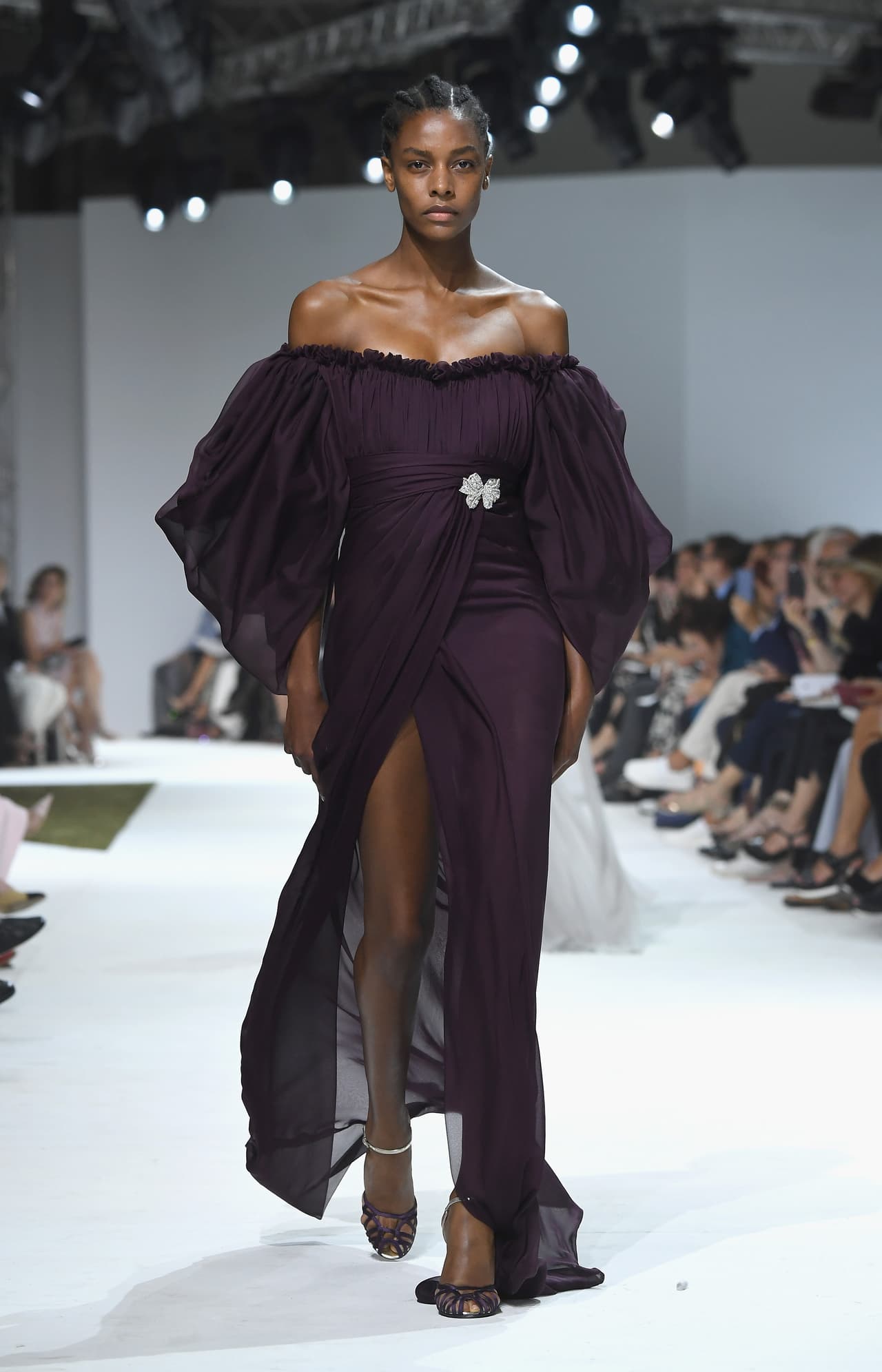 Las ampulosas mangas y alta cintura de esta fantasía sublime de Giambattista Valli, le dan un toque de inocencia a una silueta más bien sensual, con vaporosas capas de tela en tono berenjena profundo que dejan hombros y pierna al descubierto. Portar un vestido como éste requiere de algo más que simples curvas, y la soberbia Buika tiene lo que se requiere.
<br>