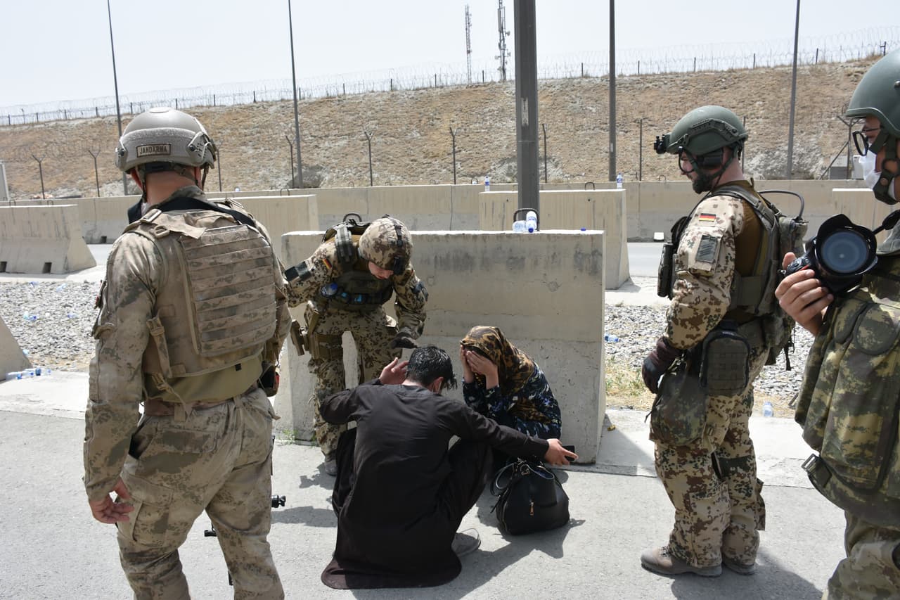 Soldados alemanes ayudan a una mujer que se desmayó por el calor dentro del aeropuerto de Kabul el 18 de agosto. Para muchos afganos ha sido imposible entrar al aeródromo, aunque fueron convocados por las embajadas.
<br>