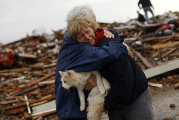 June Simson recibe un abrazo de su vecino Jo McGee tras encontrar a su gatito Sammi entre los escombros.