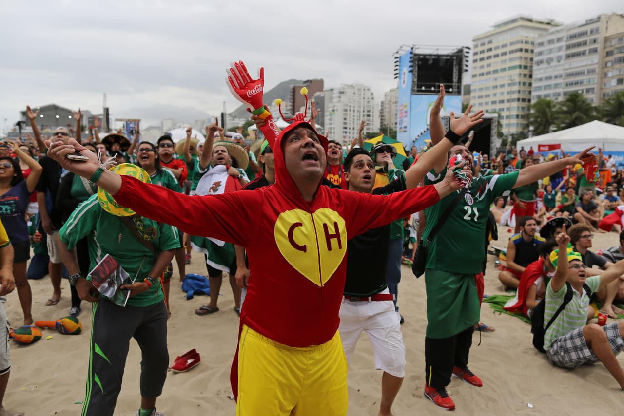 Aficionado mexicano disfrazado del personaje televisivo mexicano El Chapulín Colorado reacciona mientras ve el partido de su selección contra Camerún en una pantalla dentro del área del FIFA Fan Fest en la playa de Copacabana en Río de Janeiro, Brasil.